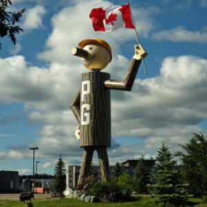 Giant wooden statue standing in a public green space.